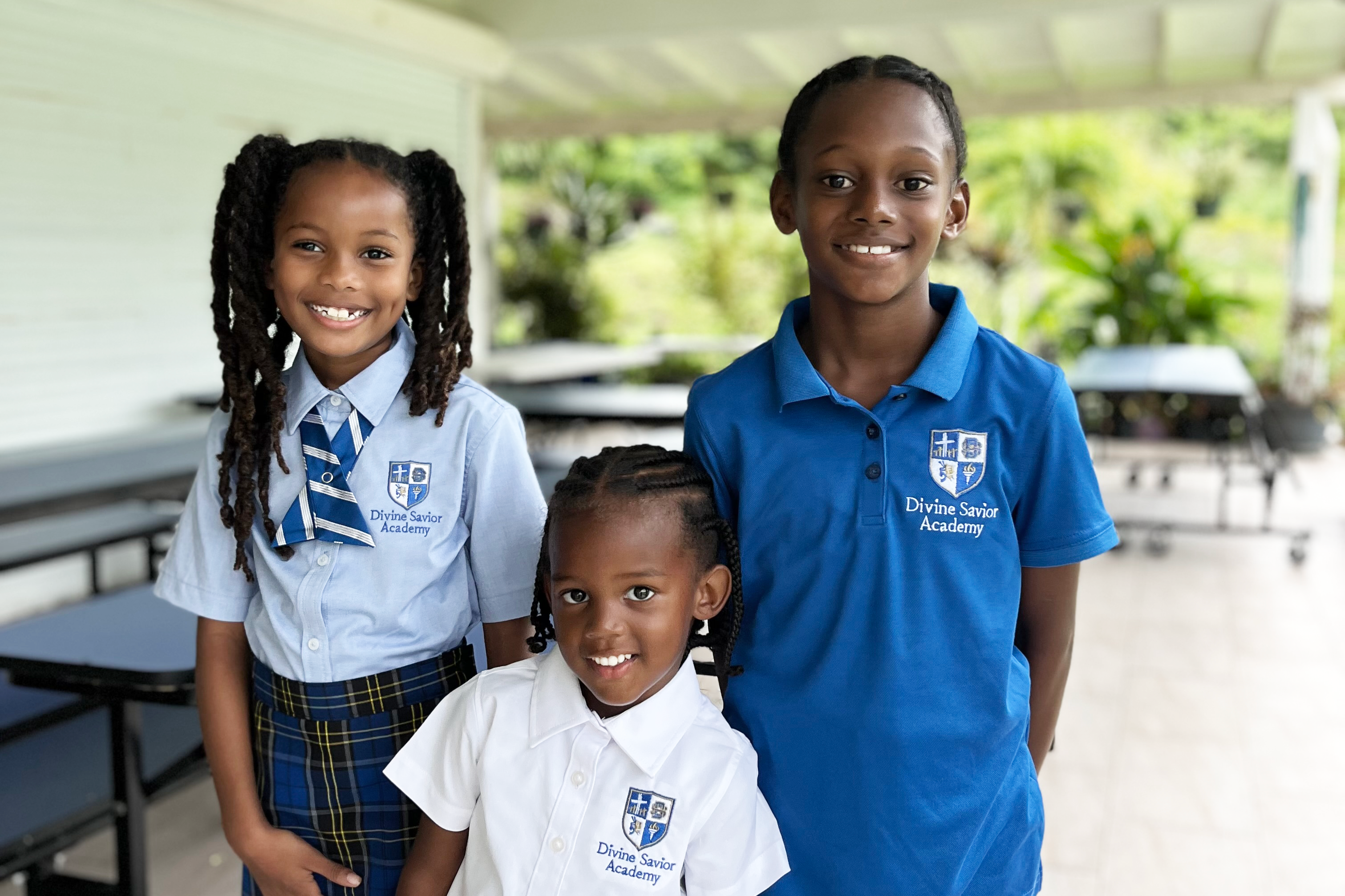 Young Divine Savior Academy students at the Grenada Campus smiling standing together in a group. 